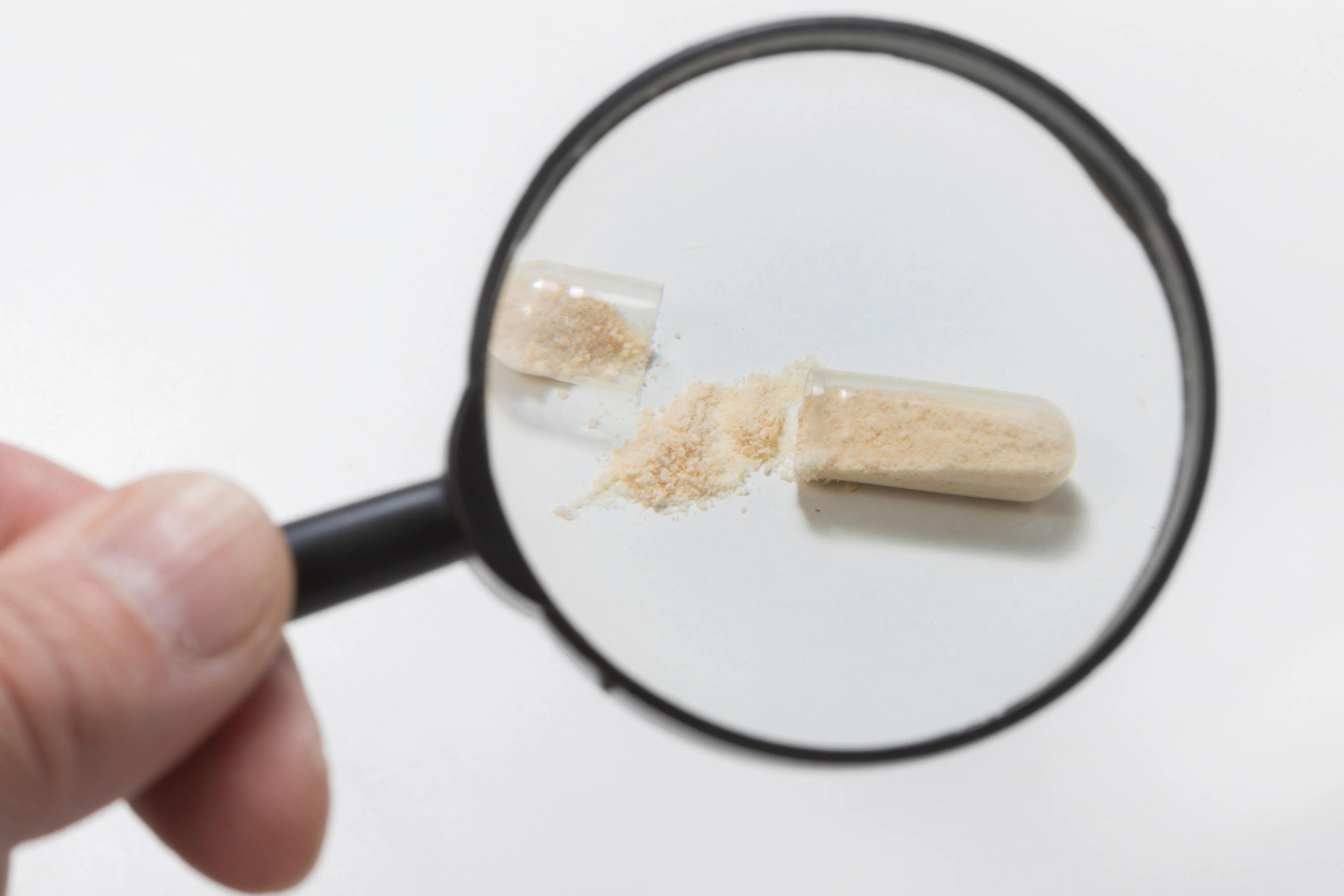 Magnifying glass inspecting a broken probiotic capsule